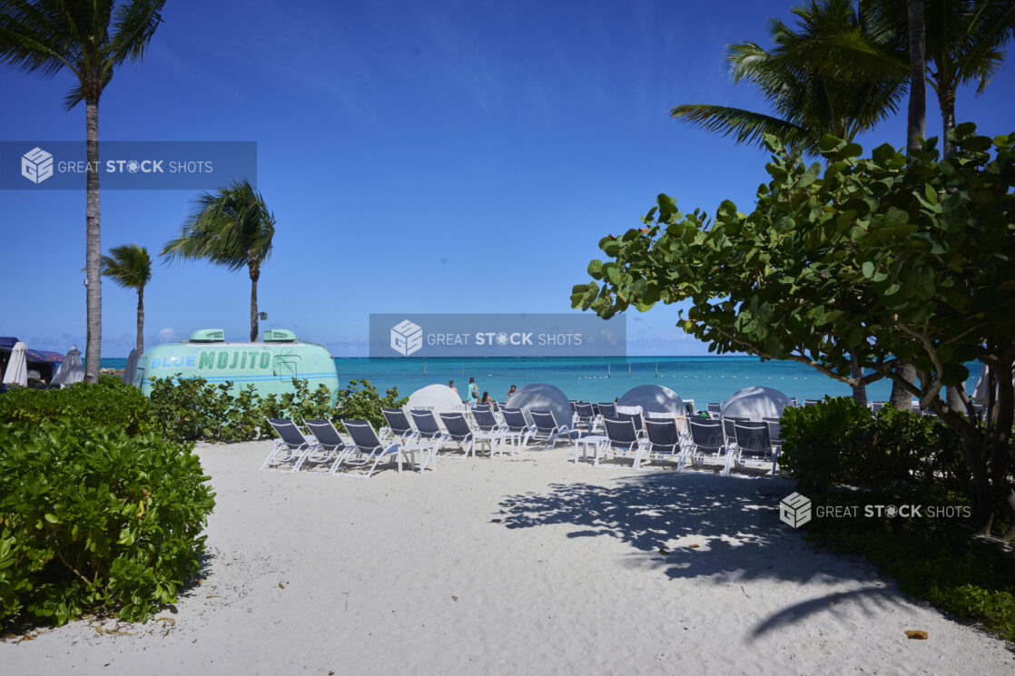 White Sandy Beach with Numerous Beach Chairs, Palms Trees Under a Clear Blue Sky with a Beachside Bar Food Truck in Nassau, Bahamas