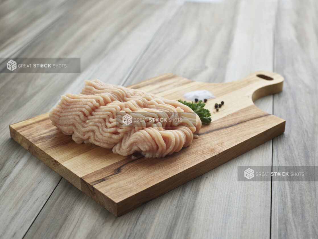 Raw ground chicken with seasonings on a wooden board, close-up, variation 1