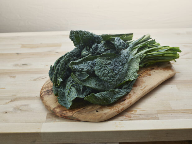 Fresh lacinato kale arranged on a wooden board, close-up