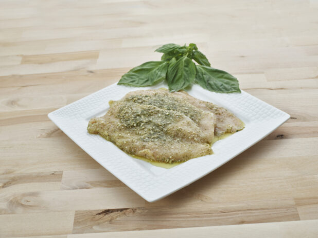 Pesto marinated seasoned chicken breast cutlets on a decorative square white plate