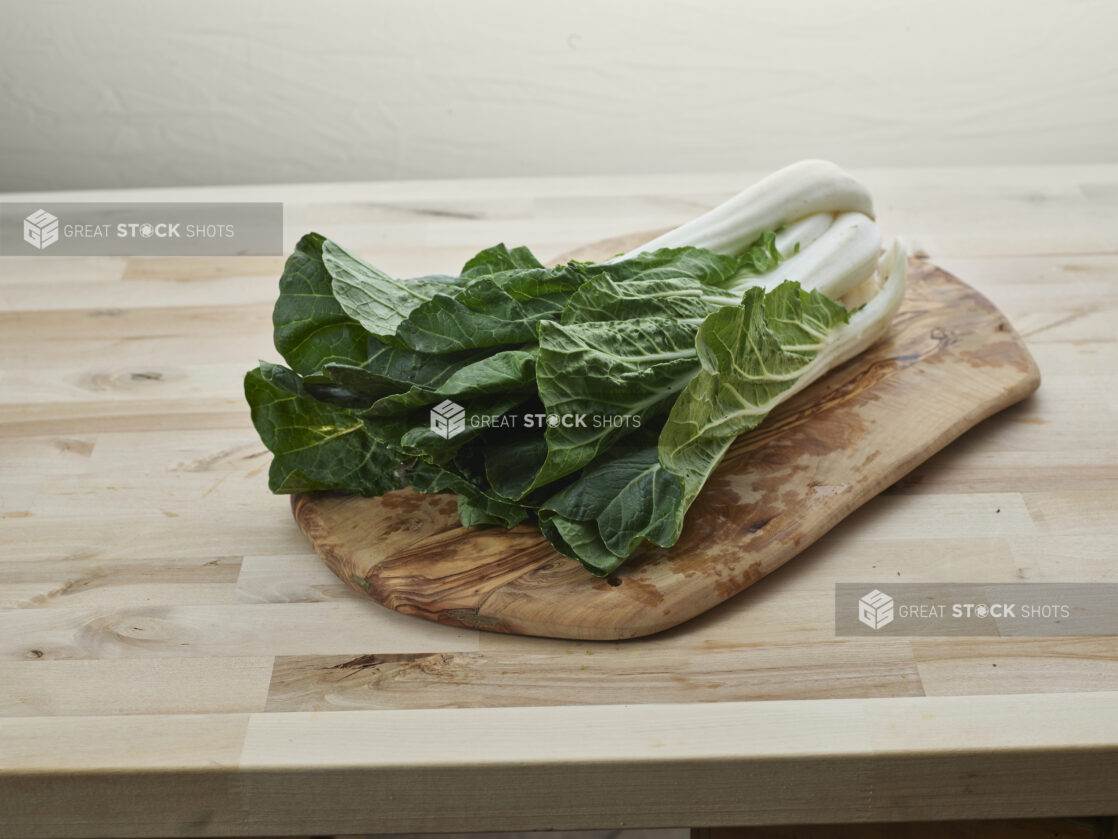 Bunch of fresh bok choy on a natural wooden board, wood background