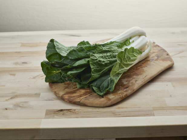 Bunch of fresh bok choy on a natural wooden board, wood background
