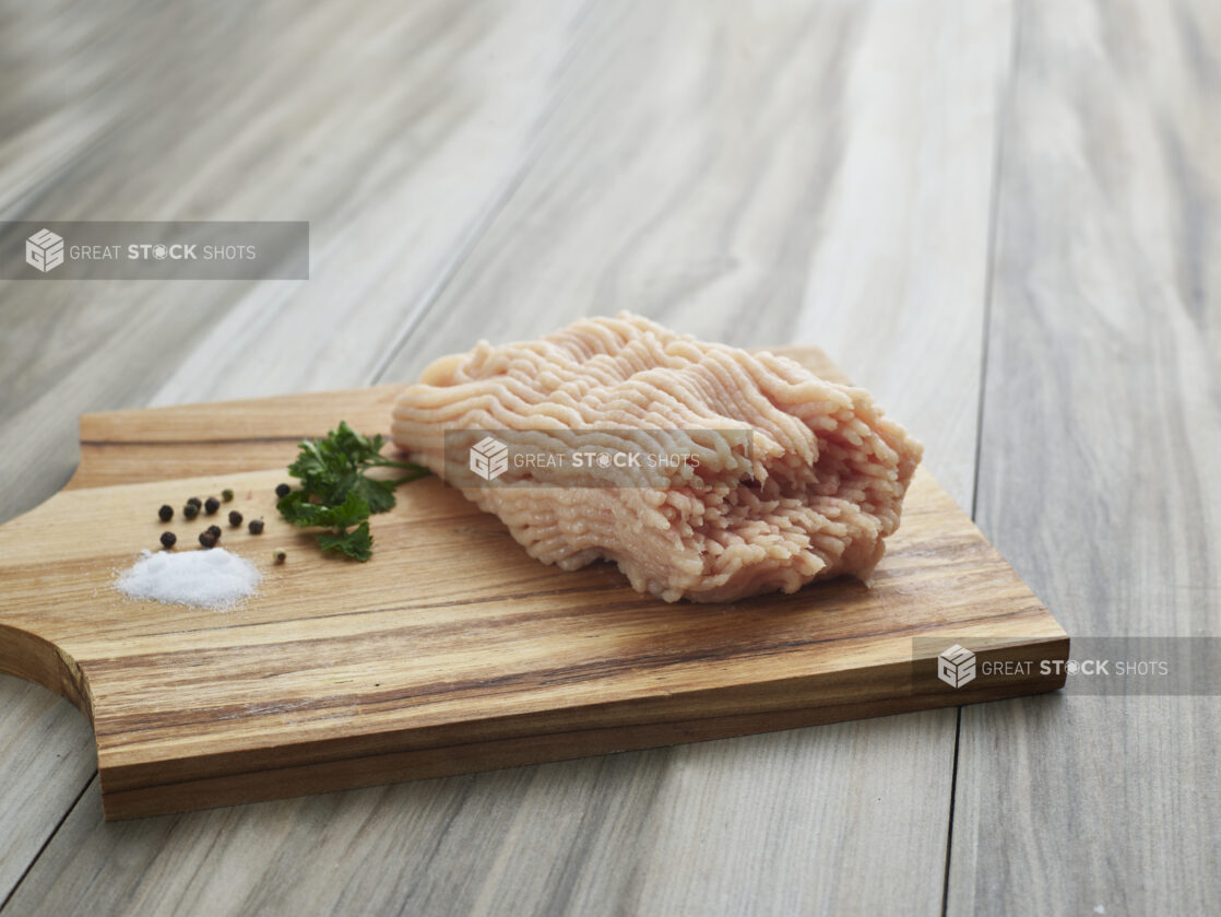 Raw ground chicken with seasonings on a wooden board, close-up, variation 2