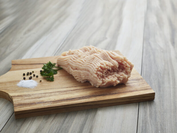 Raw ground chicken with seasonings on a wooden board, close-up, variation 2