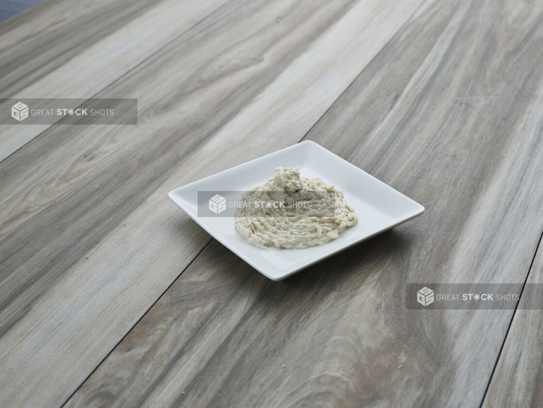 Smoked white fish salad on a square white ceramic plate, close-up