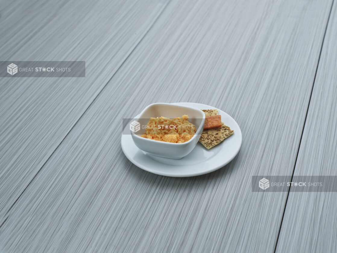 Hot horseradish spread in a white ceramic ramekin, plated with a few chips and crackers