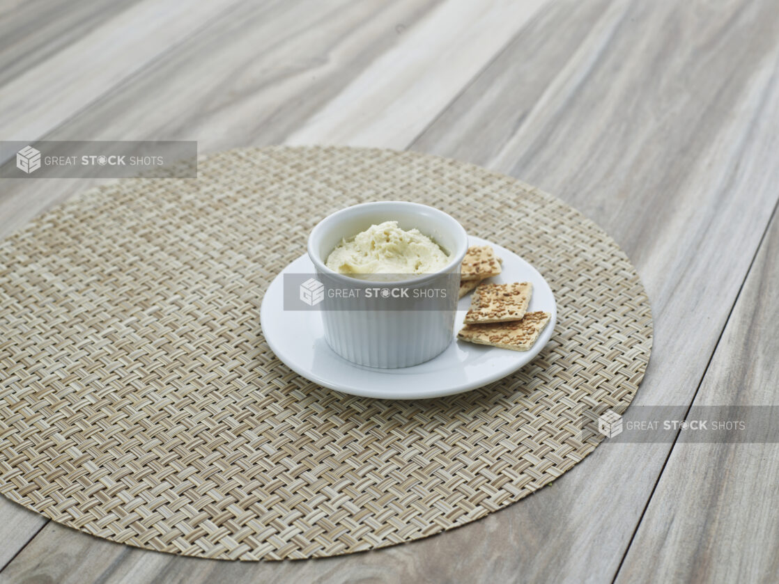 Swiss roquefort cheese spread in a round white ramekin, plated with a few flatbread crackers