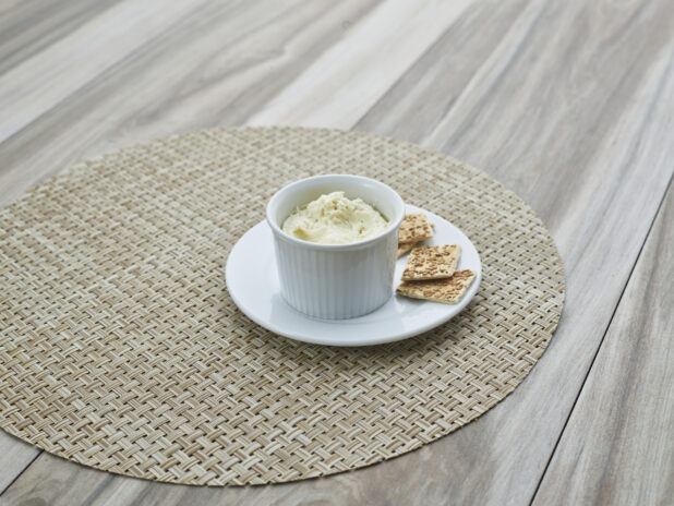 Swiss roquefort cheese spread in a round white ramekin, plated with a few flatbread crackers