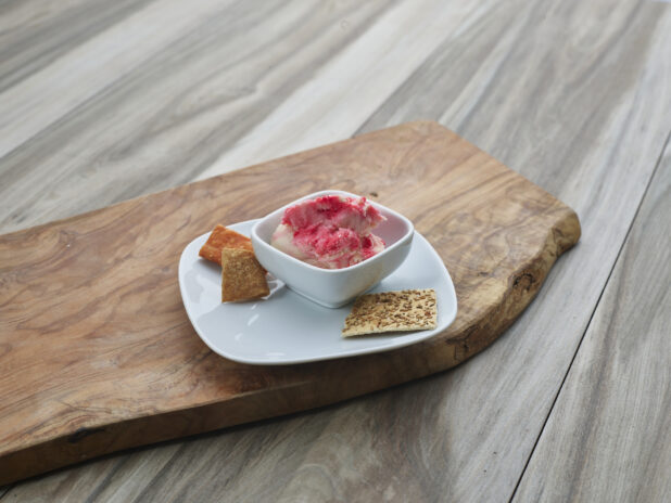 Provolone and chianti cheddar spread in a plated white ramekin on a natural wood board