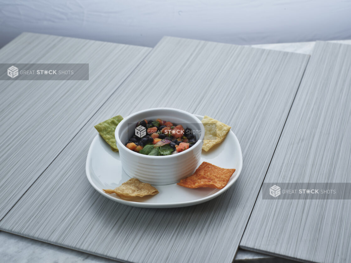 Black bean and papaya salsa in a small white bowl, plated with corn chips