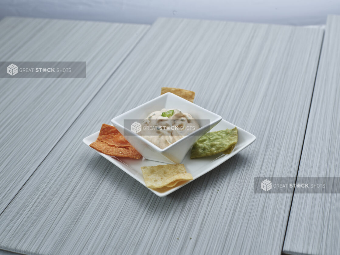 Southwestern-style creamy dip in a plated white ramekin surrounded by multicoloured tortilla chips