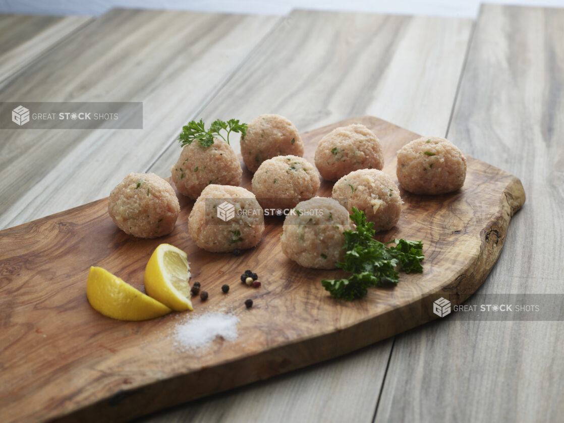 Chicken meatballs with seasonings on a natural wood board, close-up