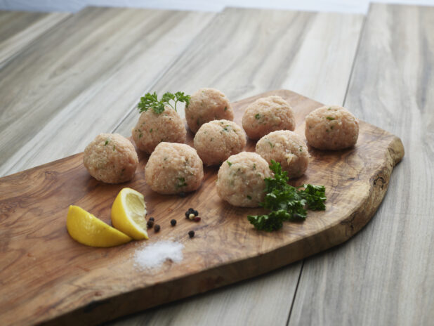 Chicken meatballs with seasonings on a natural wood board, close-up