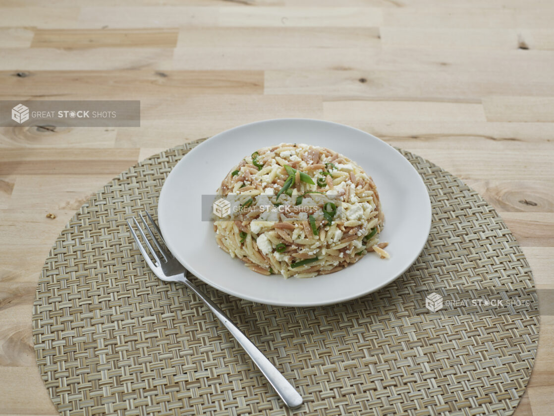 Toasted orzo salad in a mound on a white plate