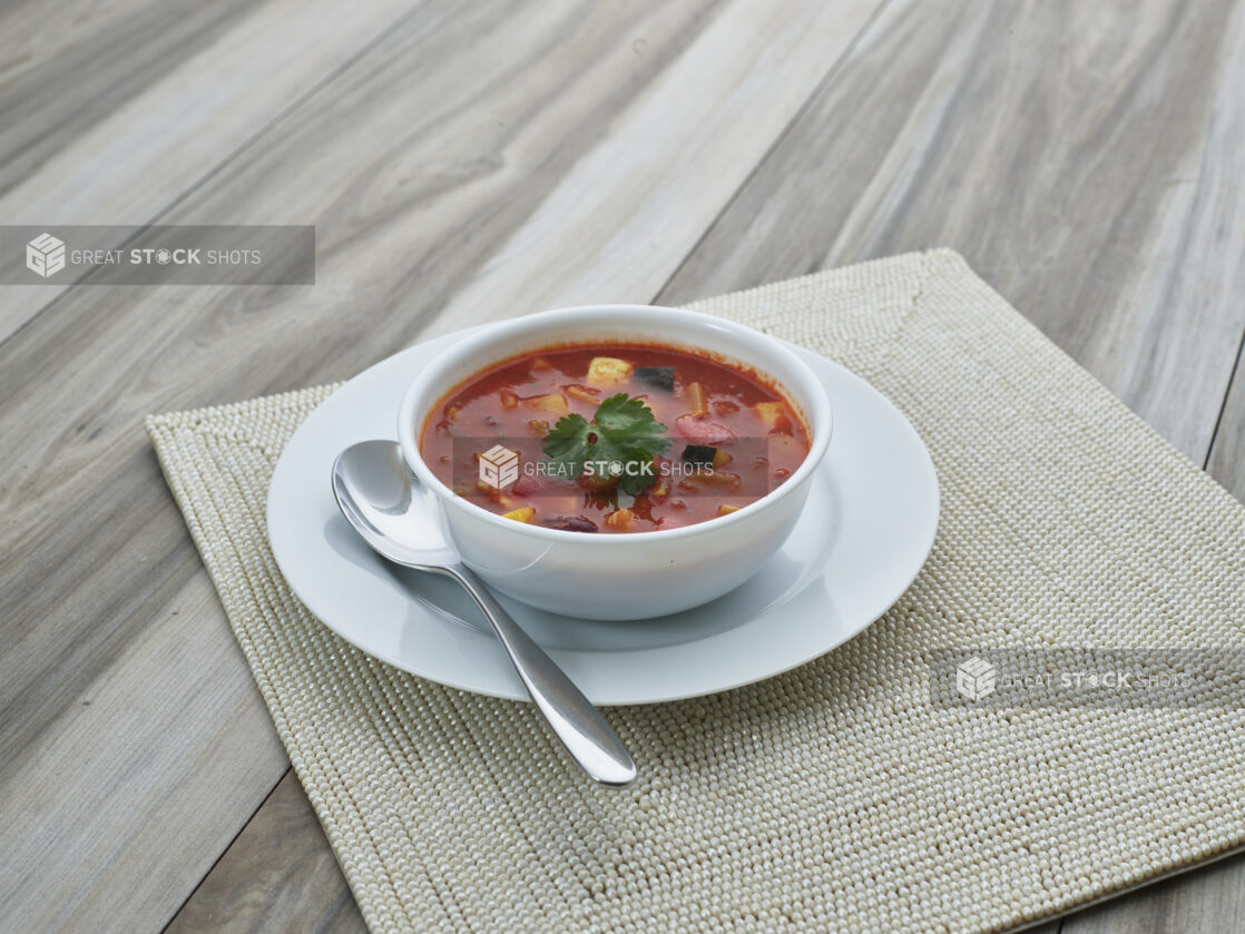 Small white ceramic bowl of vegetarian chili on a white plate