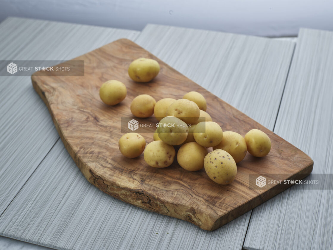 White new potatoes piled on a natural wood board, close-up