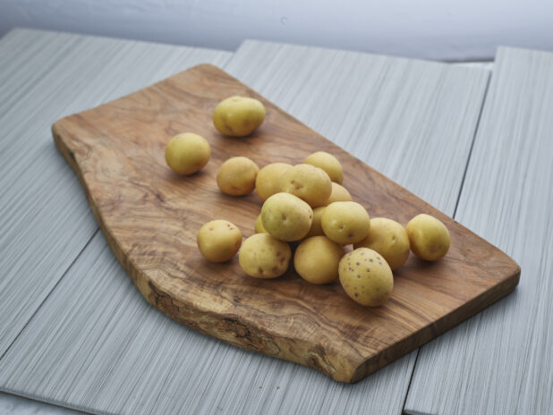 White new potatoes piled on a natural wood board, close-up