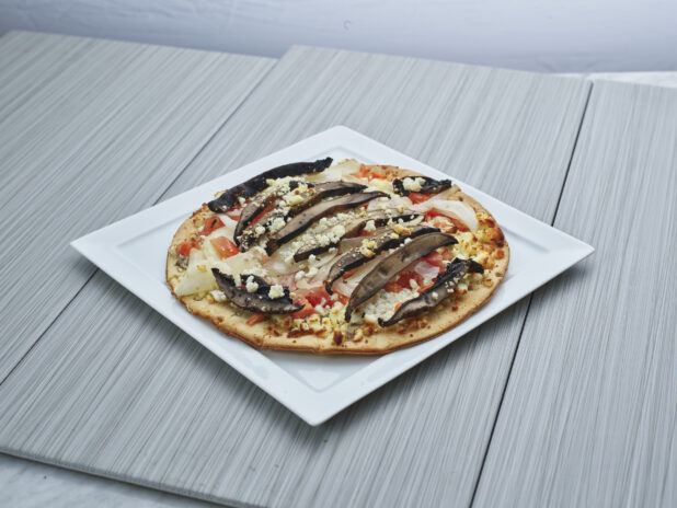 Personal-size thin-crust portobello and cauliflower pizza on a square white plate