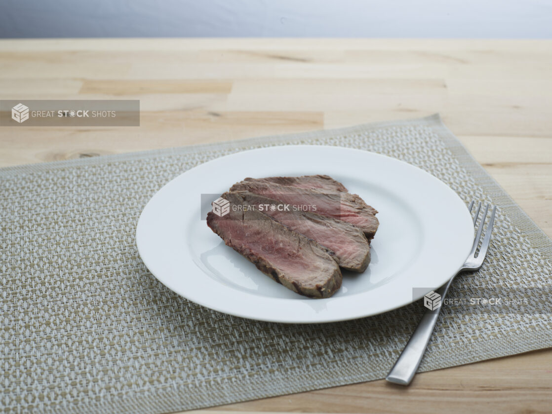 Slices of London broil steak arranged on a white plate