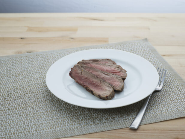 Slices of London broil steak arranged on a white plate