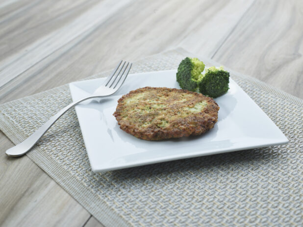 Golden fried broccoli cake with florets on a square white plate, close-up