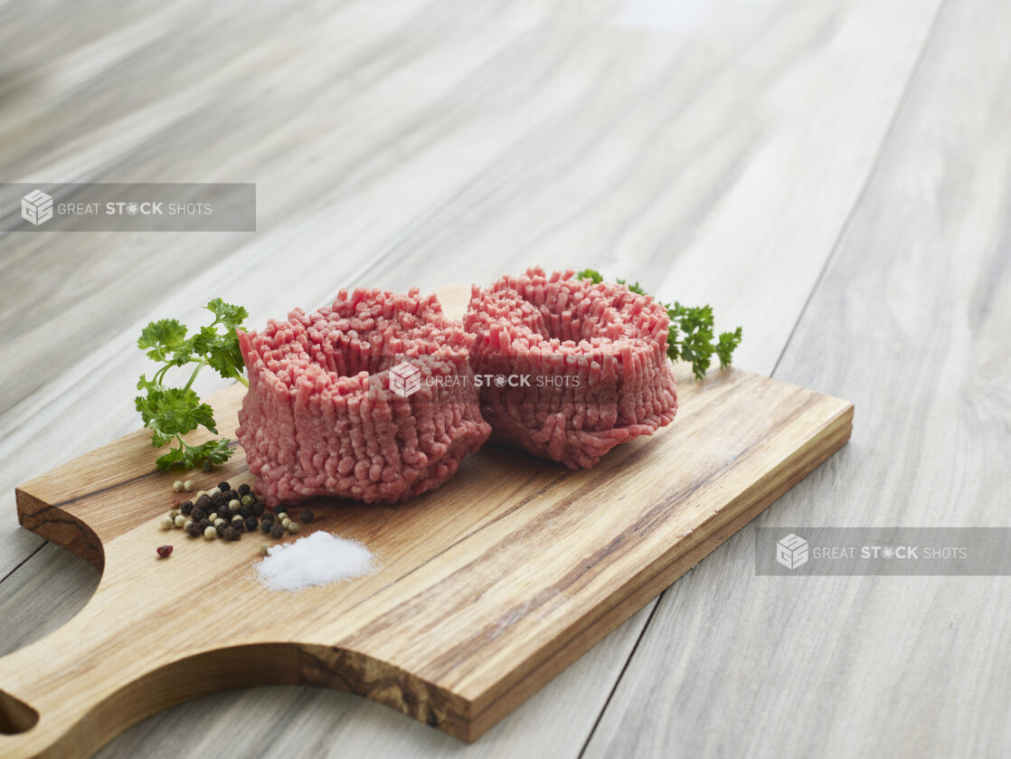 Freshly ground lamb with seasonings on a wooden paddle, close-up