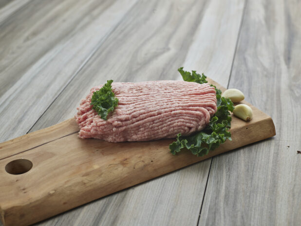 Raw ground pork with cloves of garlic on a wooden board, close-up, variation 2