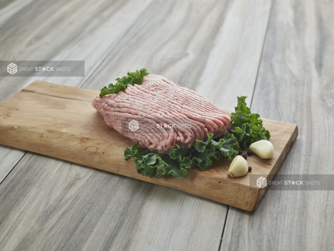 Raw ground pork with cloves of garlic on a wooden board, close-up, variation 1