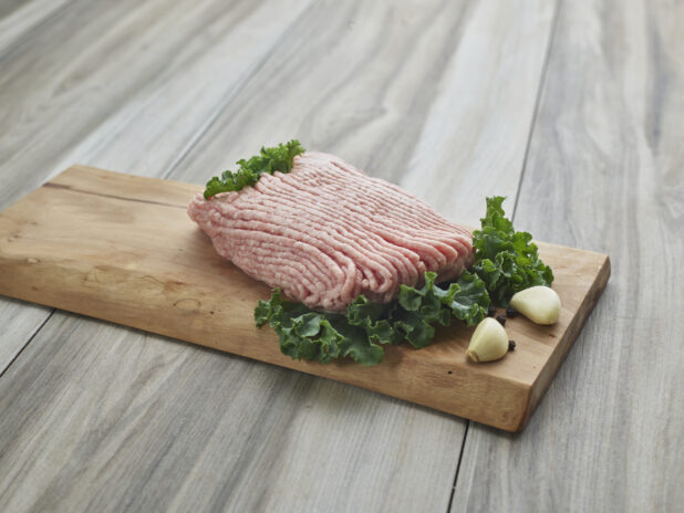Raw ground pork with cloves of garlic on a wooden board, close-up, variation 1