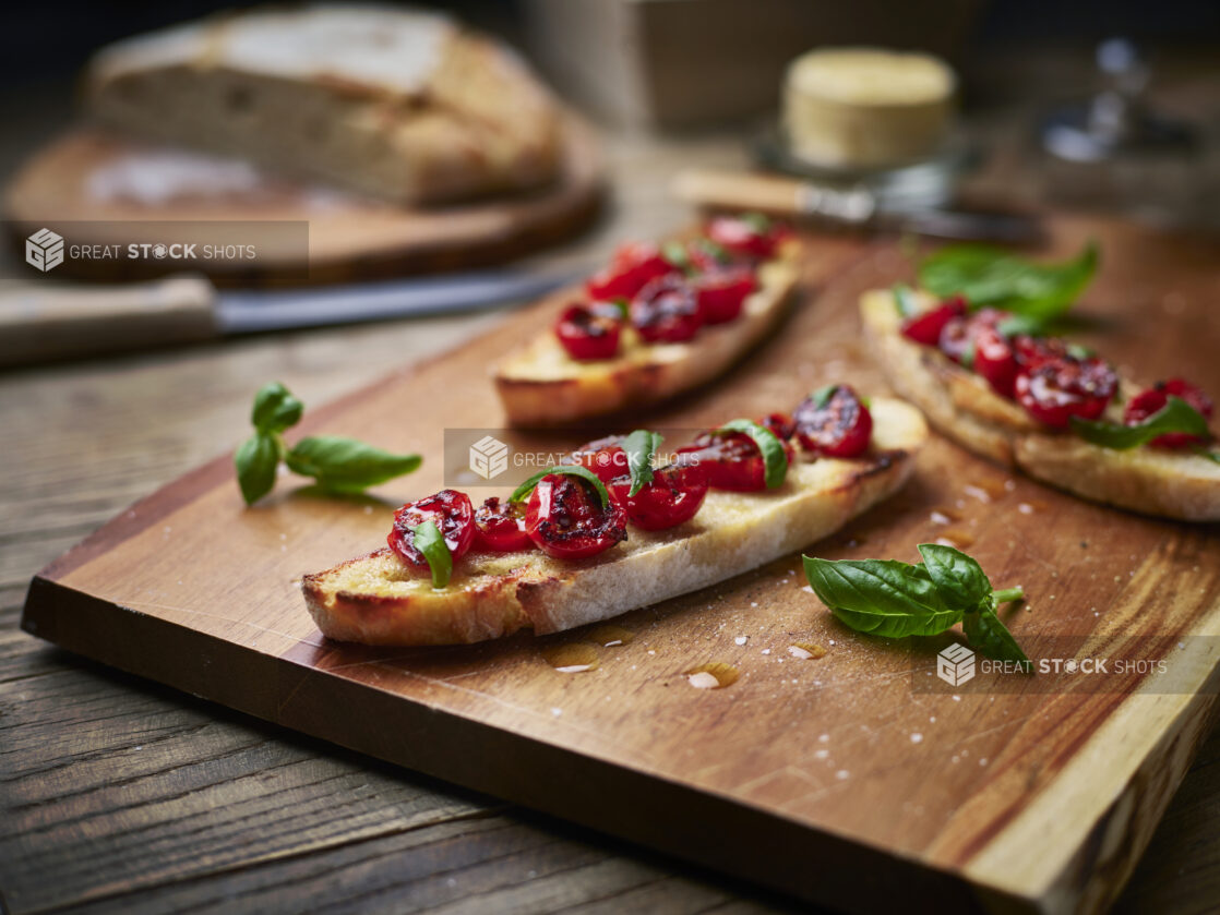 Long, thin slices of bruschetta with blistered cherry tomatoes and fresh basil, close-up