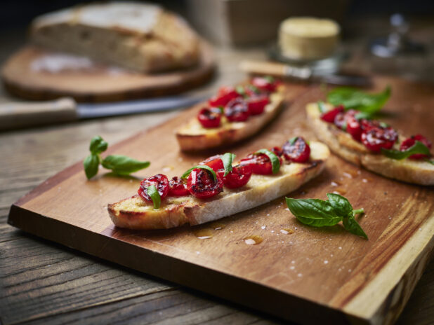 Long, thin slices of bruschetta with blistered cherry tomatoes and fresh basil, close-up