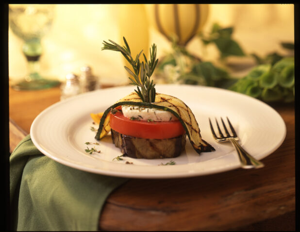 Vegetable Napoleon with Grilled Zucchini and Eggplants, Tomato and Goat Cheese on a White Ceramic Plate in an Indoor Setting