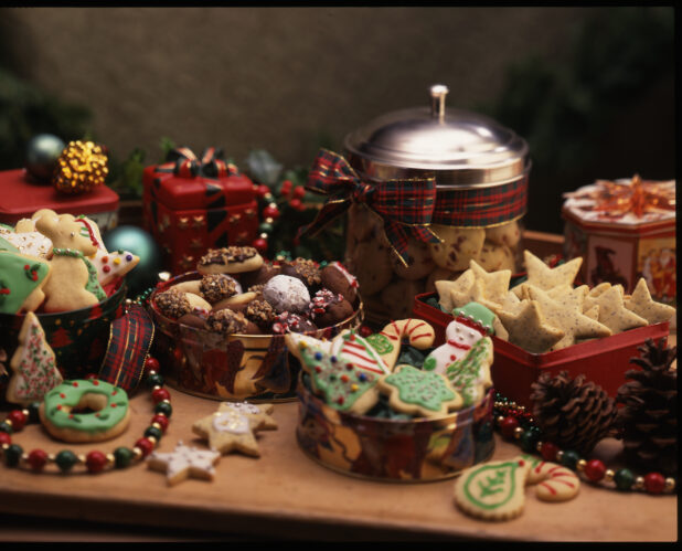 Holiday and Christmas Themed Cookies in Tins Surrounded by Christmas Decorations in a Cookie Exchange Setting Indoors