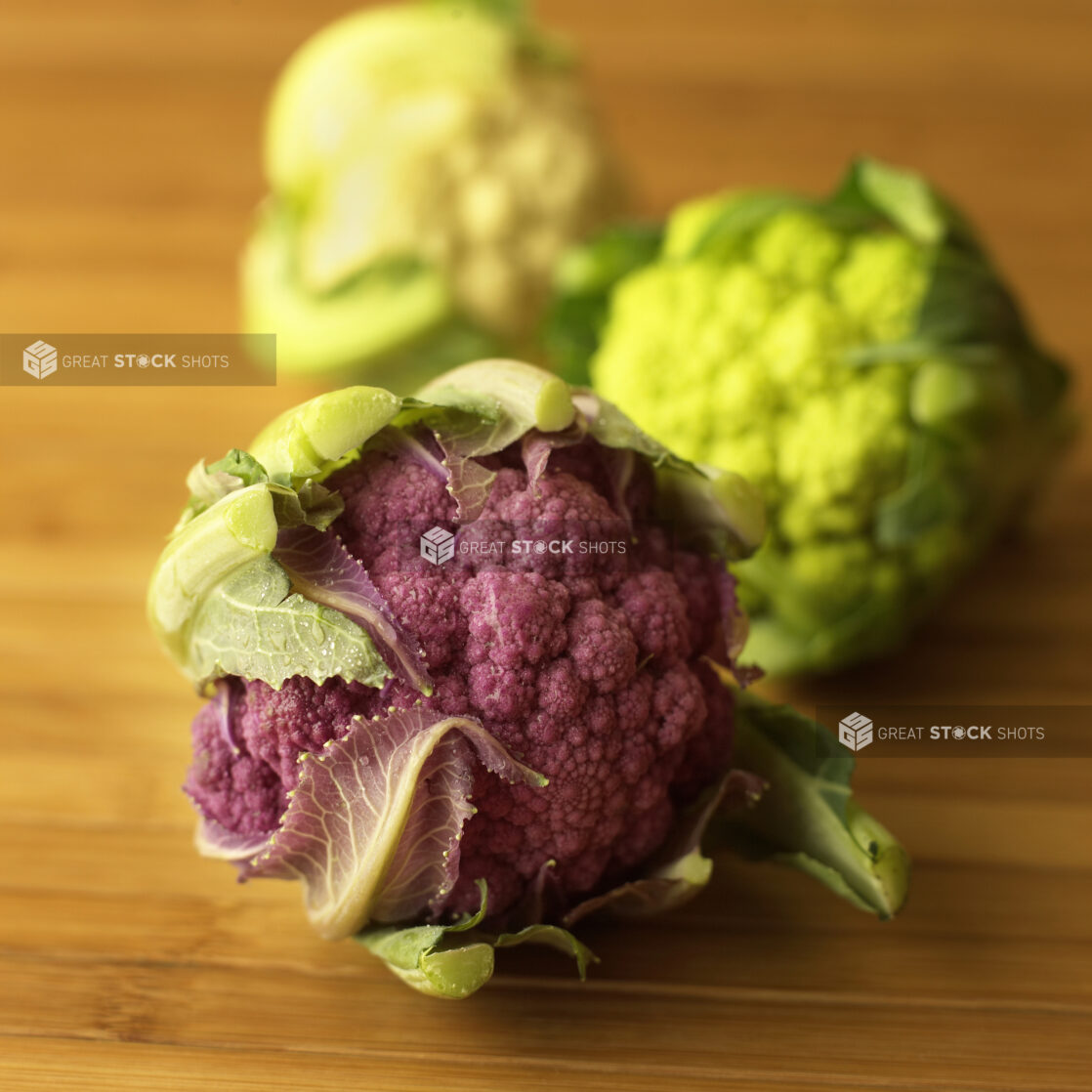 Close up of Purple and White Cauliflower Heads on a Wooden Table