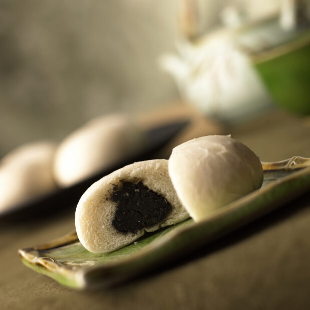 Close Up of Cut Halves of Steamed Chinese Red Bean Paste Buns on a Ceramic Dish