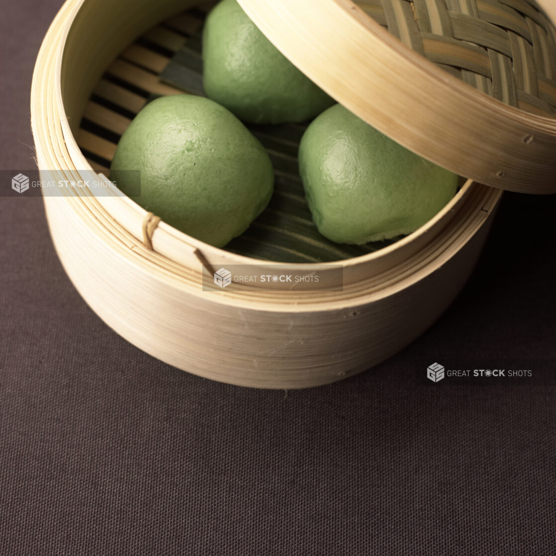 Close Up of a Dum Sum Bamboo Steamer with Fluffy Green Steamed Buns or Bao