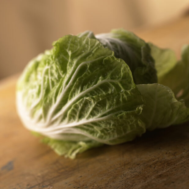 Close Up View of a Head of Nappa/Chinese Cabbage on a Wooden Board