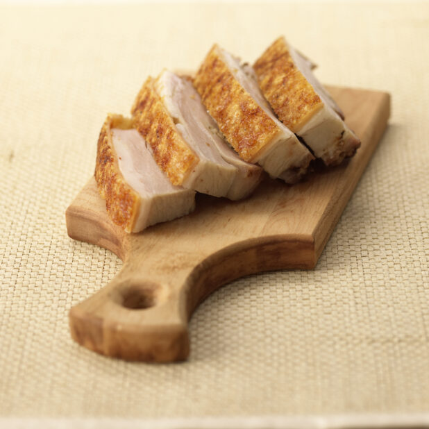 Close Up of Slices of Siu Yuk - Cantonese-Style Crispy Pork Belly - on a Wooden Platter