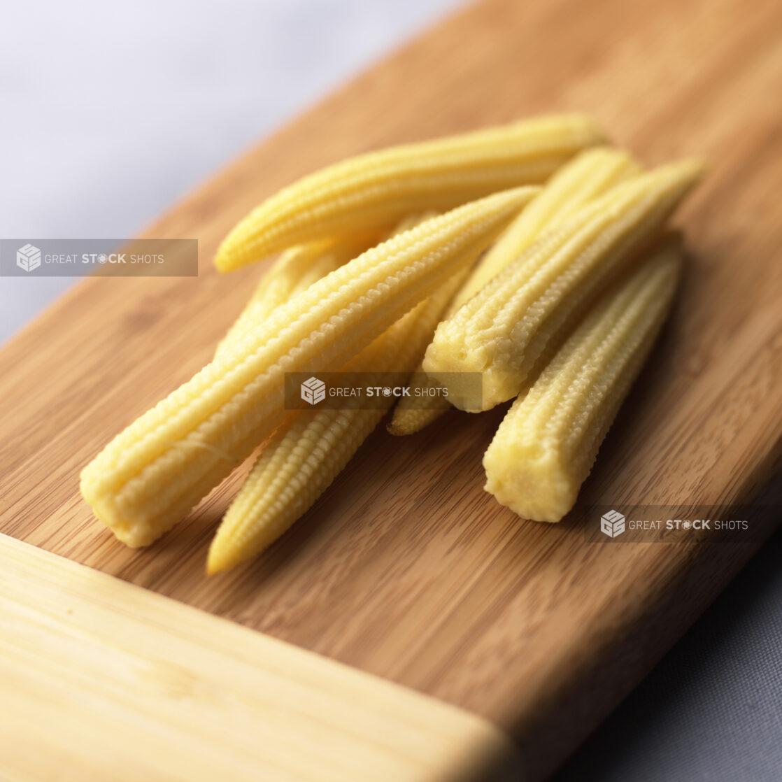 Close Up of a Bunch of Baby Corn or Cornlettes on a Wooden Cutting Board