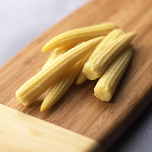 Close Up of a Bunch of Baby Corn or Cornlettes on a Wooden Cutting Board