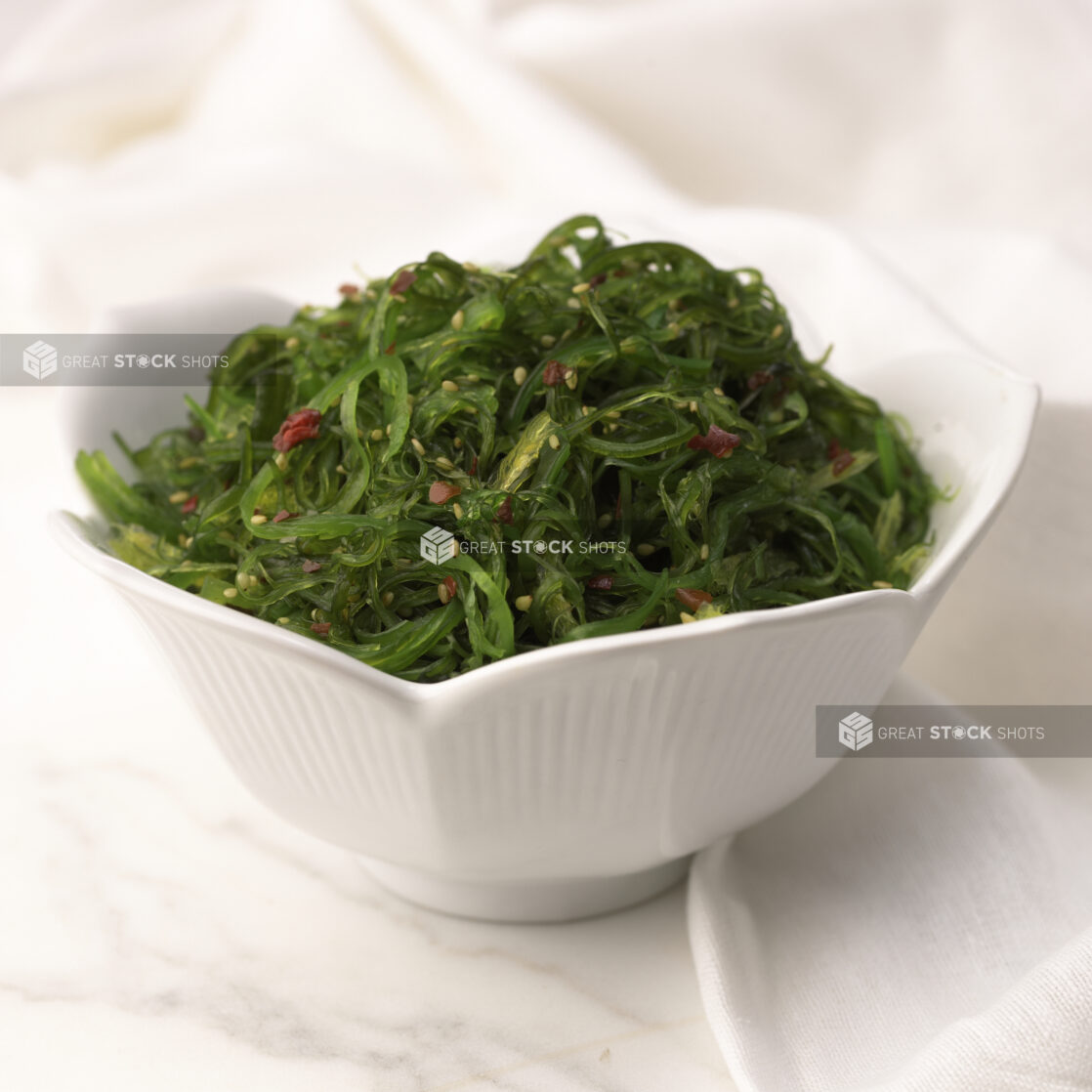 Close Up of a White Ceramic Bowl of Seaweed Salad on a Marble Surface