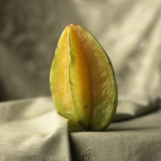 A Whole Star Fruit on its End Sitting on a Tablecloth Surface