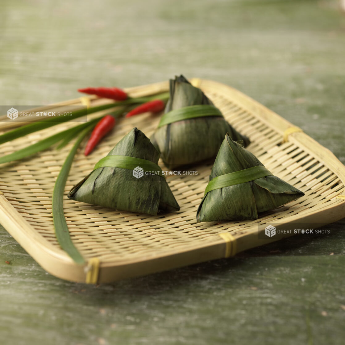 Close Up of Zongzi - Chinese Sticky Rice Dumplings Wrapped and Steamed in Bamboo Leaves - on a Bamboo Platter