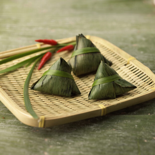Close Up of Zongzi - Chinese Sticky Rice Dumplings Wrapped and Steamed in Bamboo Leaves - on a Bamboo Platter