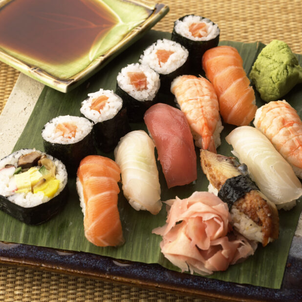 Close Up of an Assorted Sushi Platter with Popular Nigiri and Maki Sushi with Pickled Ginger, Soy Sauce and Wasabi Paste on the Side