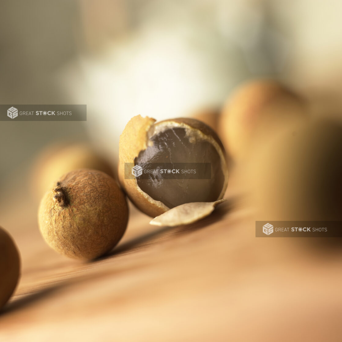 Close Up of Longan – a Type of Chinese Fruit – Scattered on a Table With One Peeled Showing the Flesh Inside