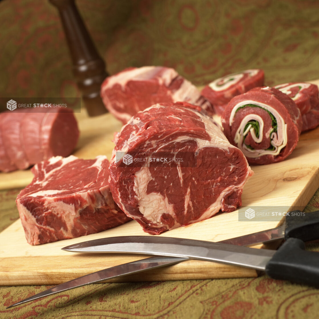 Assorted Cuts of Beef Steak Meat on a Wooden Cutting Board in an Indoor Setting