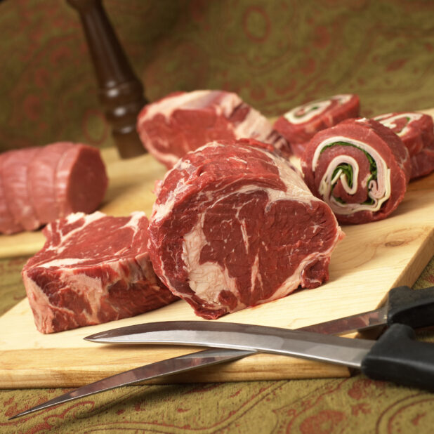 Assorted Cuts of Beef Steak Meat on a Wooden Cutting Board in an Indoor Setting