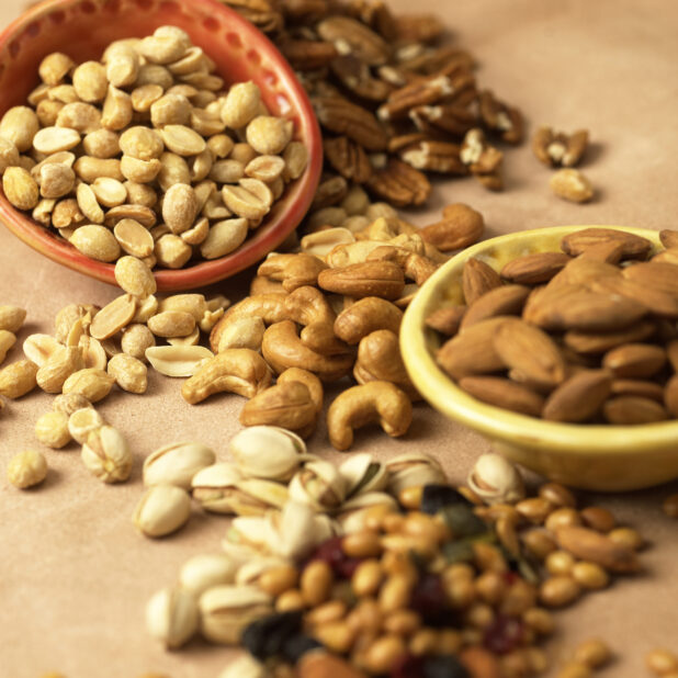 Close Up of Assorted Nuts - Cashews, Peanuts, Almonds, Pistachios and Pecans - in an Indoor Setting