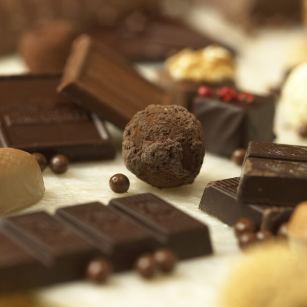 Close Up of a Chocolate Truffle Ball Surrounded by Other Chocolates in an Indoor Setting
